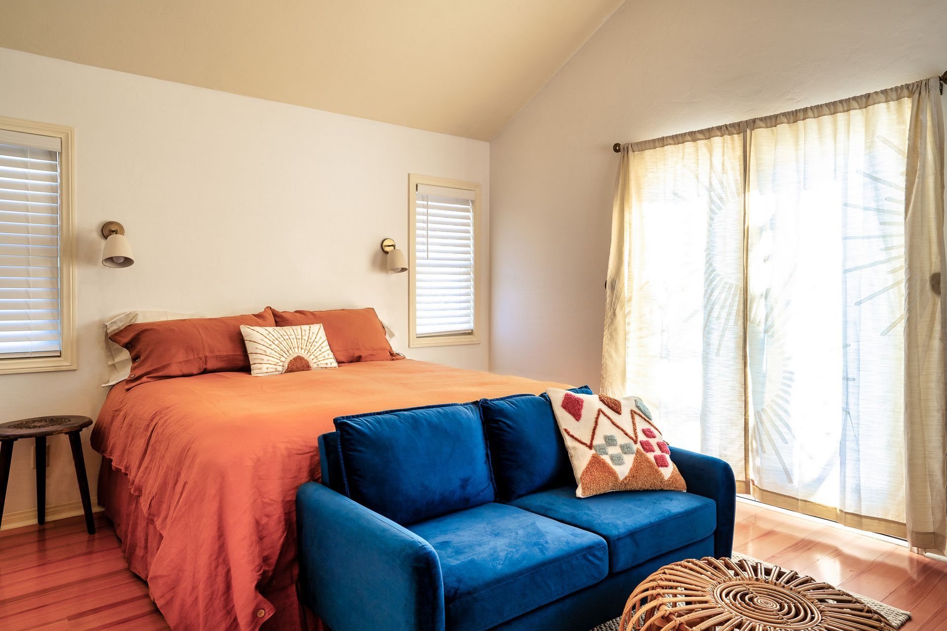 A bedroom with a bed , couch , and sliding glass doors.