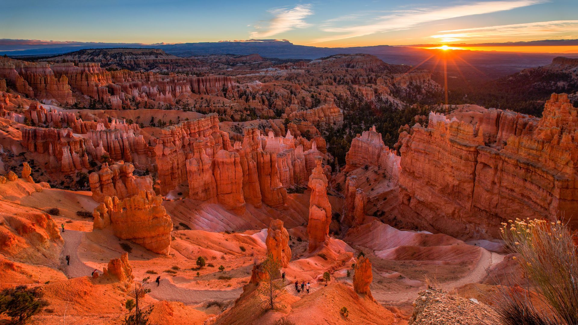 The sun is setting over a canyon with a lot of rocks.