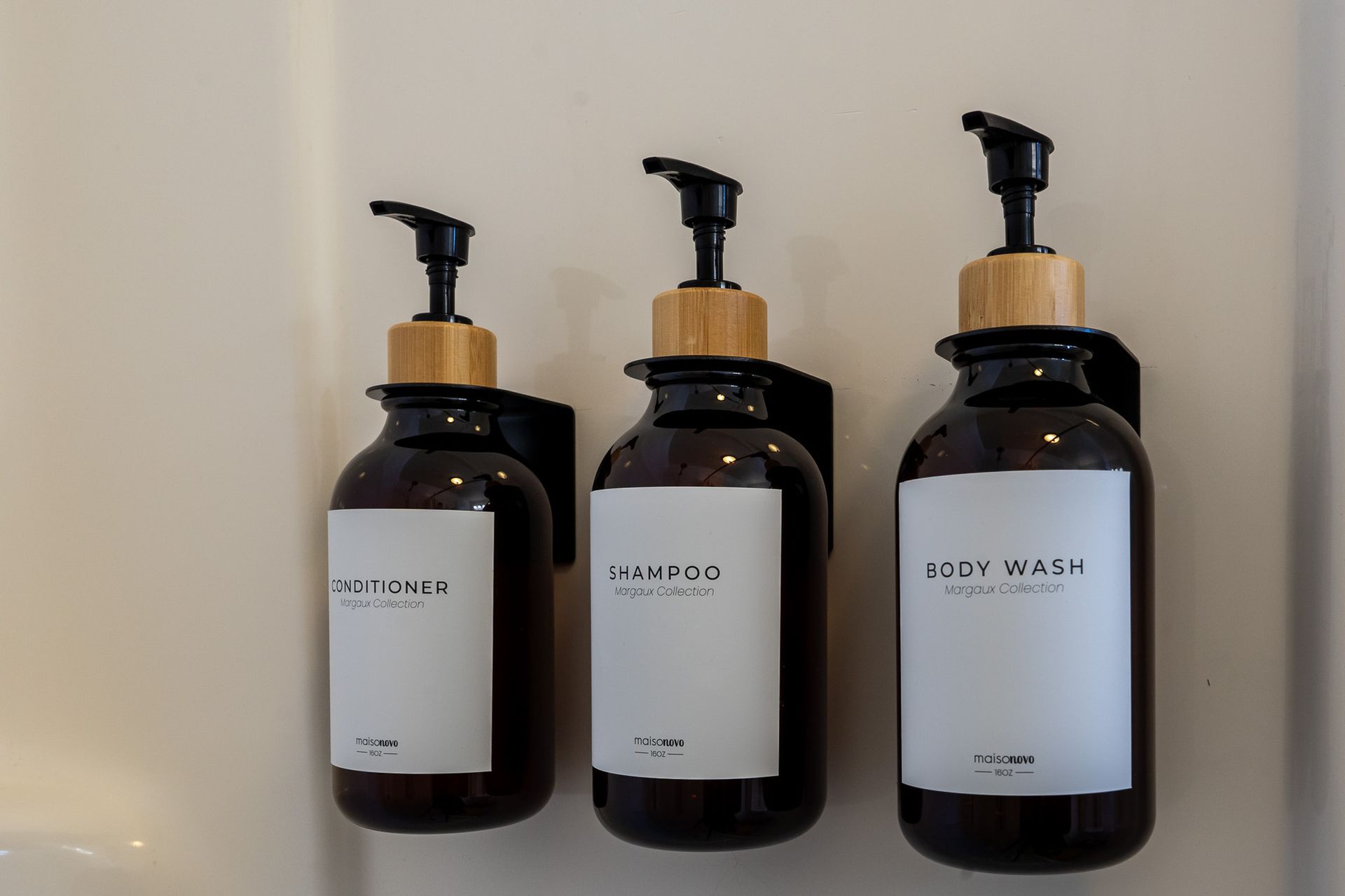 Three bottles of soap are hanging on a wall.