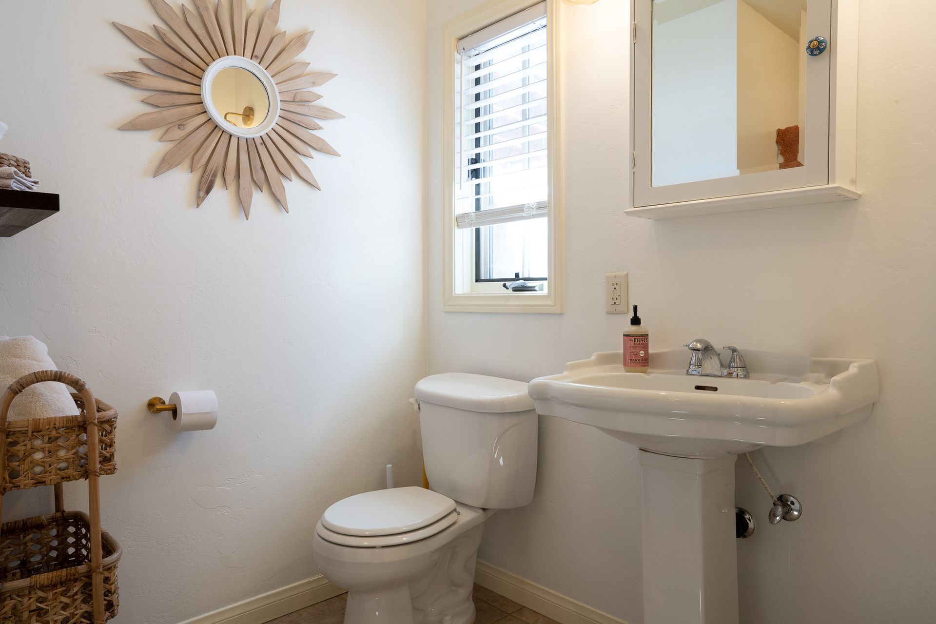 A bathroom with a toilet , sink and mirror.
