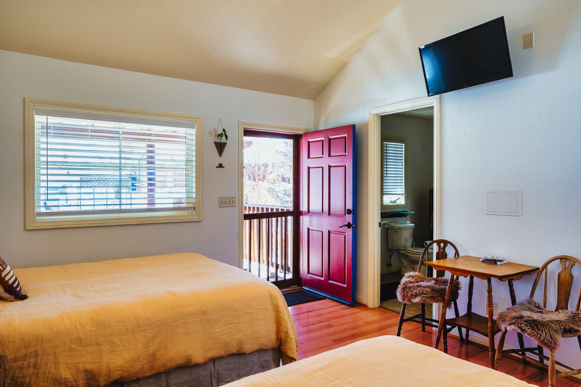 A hotel room with two beds , a table , chairs and a television.