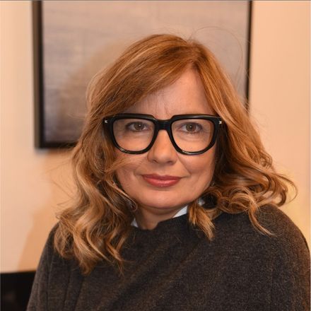 Una donna che indossa occhiali e un maglione nero sorride