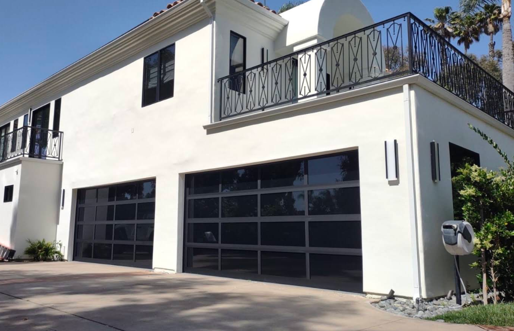 Modern white two-story house with black garage doors and rooftop terrace