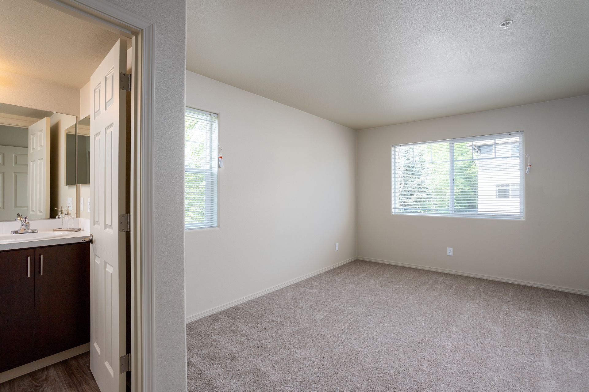 An empty bedroom with a sink and a window.