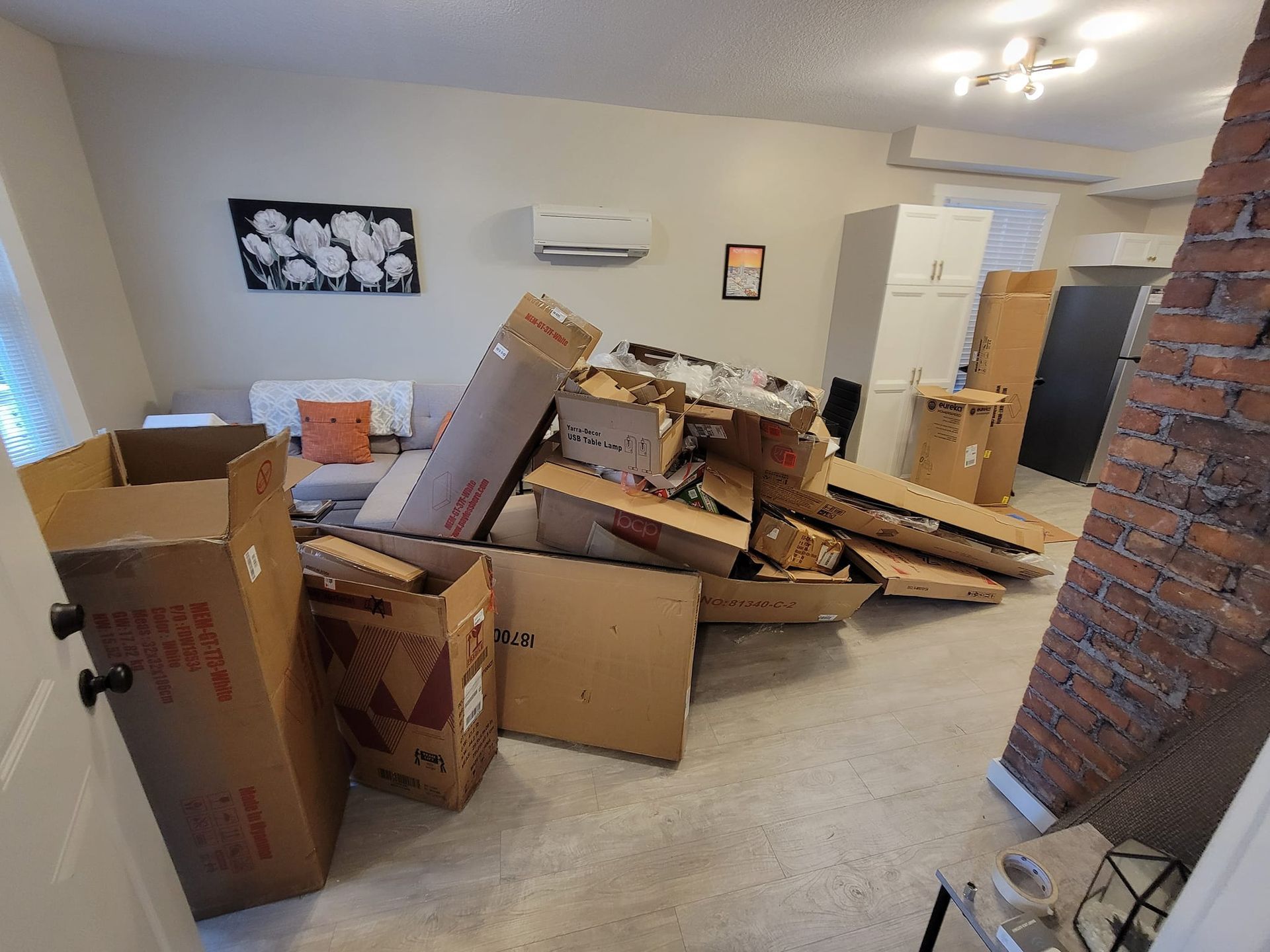 Room with a pile of cardboard boxes, furniture, and debris.