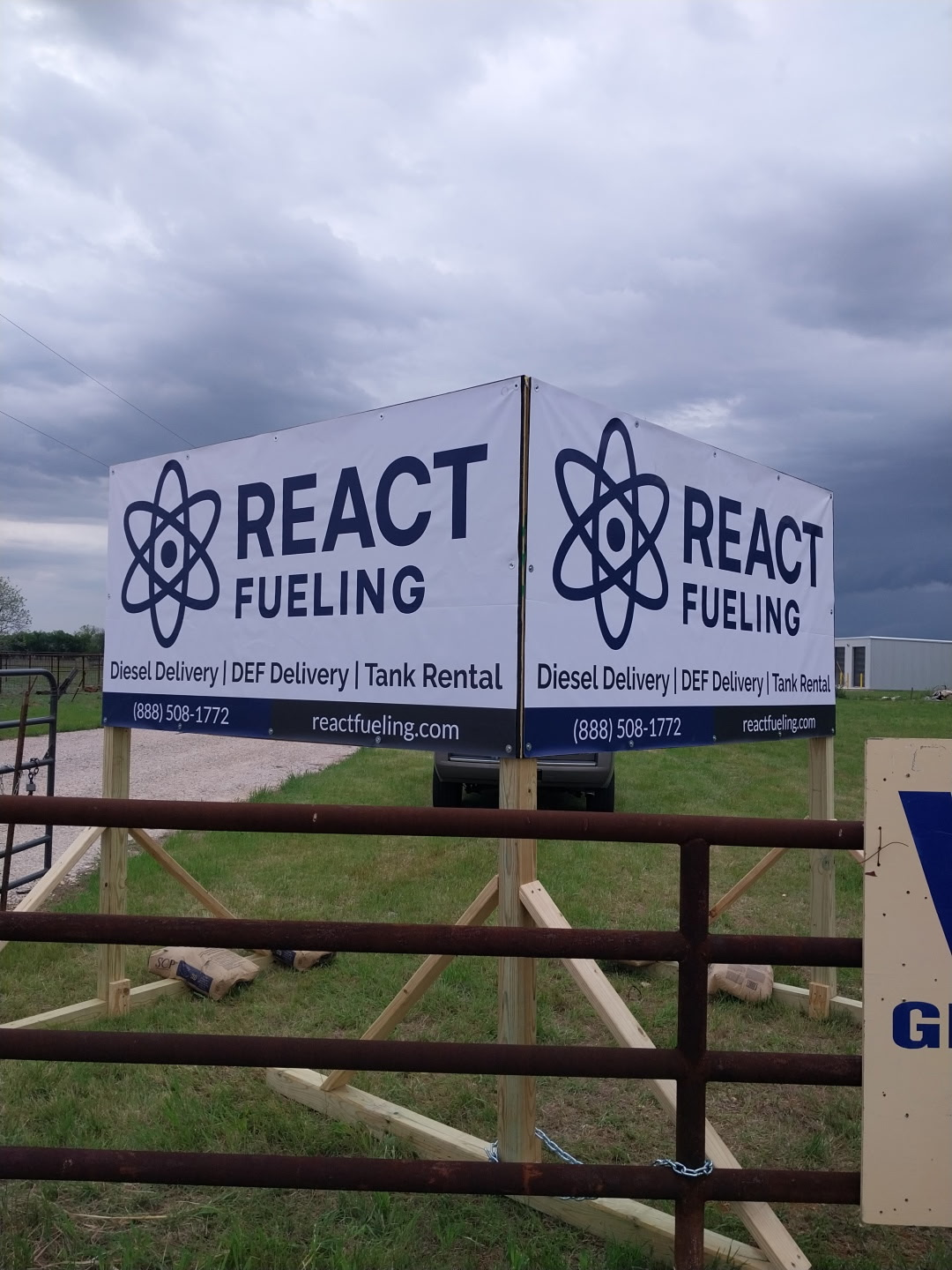React Fueling roadside sign on a wooden gate under a cloudy sky