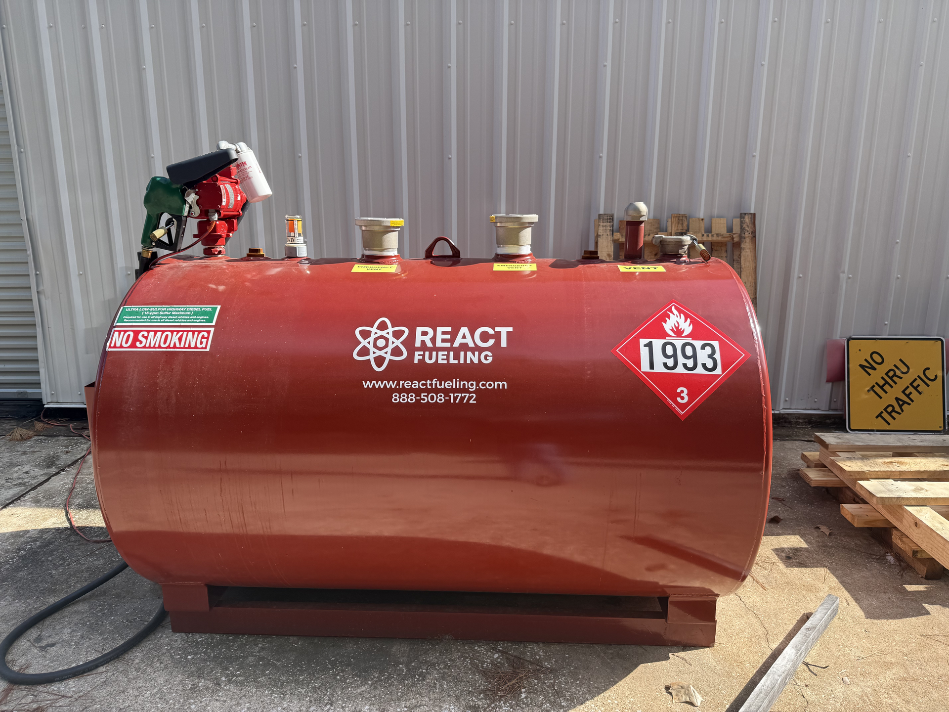 Red fuel tank with pumps and hoses labeled React Petroleum, parked outdoors