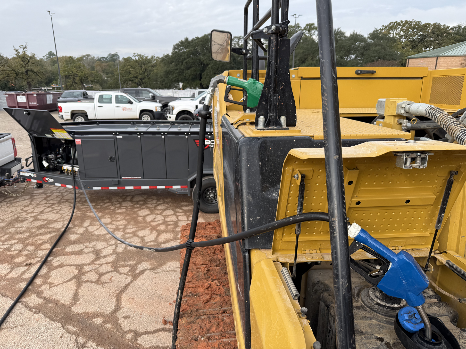 Yellow utility equipment and a black trailer with cables in a parking lot area
