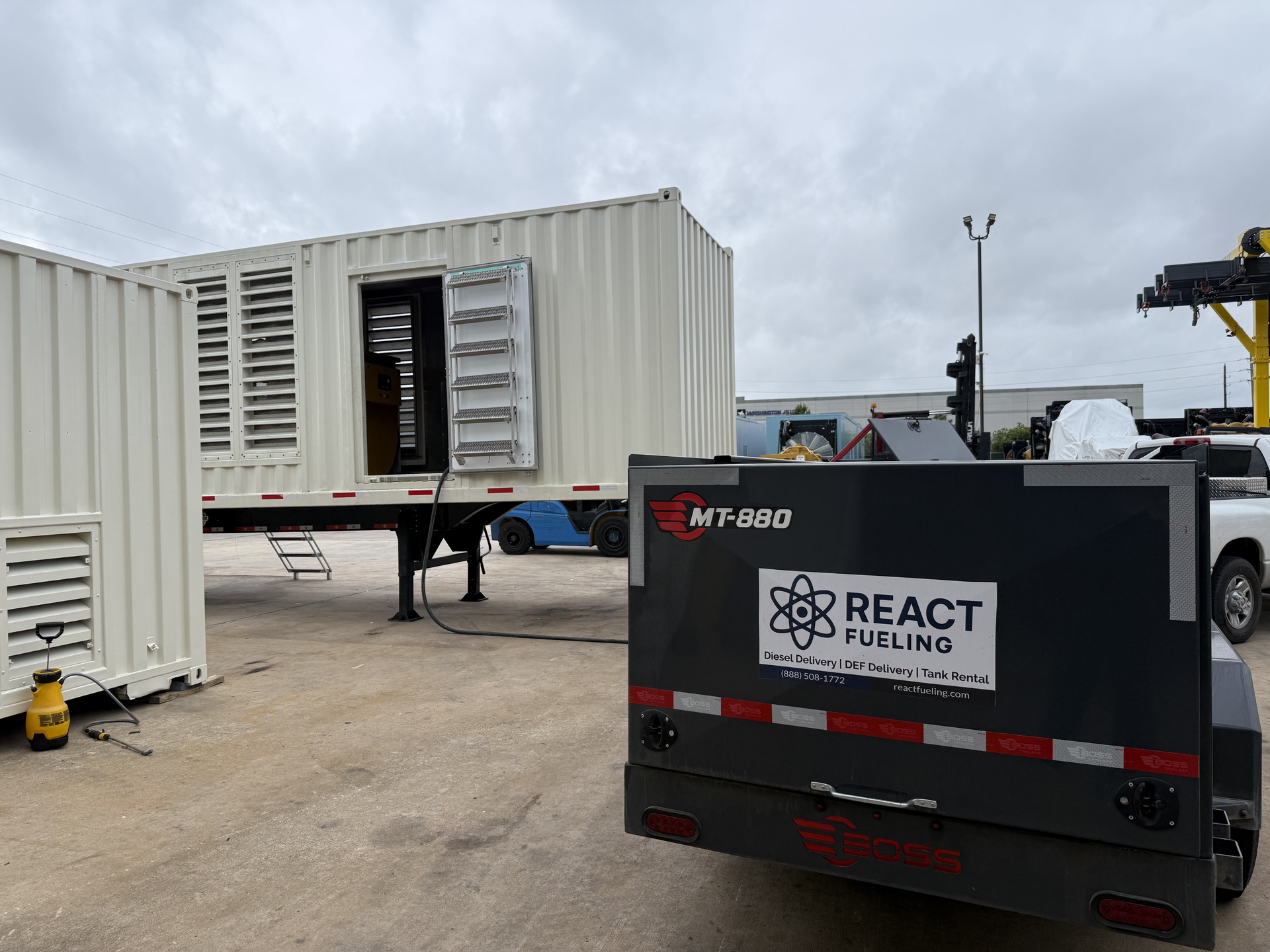 Black REACT Rentals generator in front of a white shipping container at an outdoor worksite.