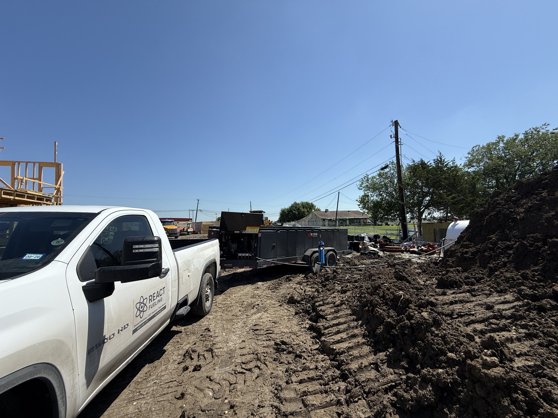 White pickup truck on a muddy construction site under a clear blue sky