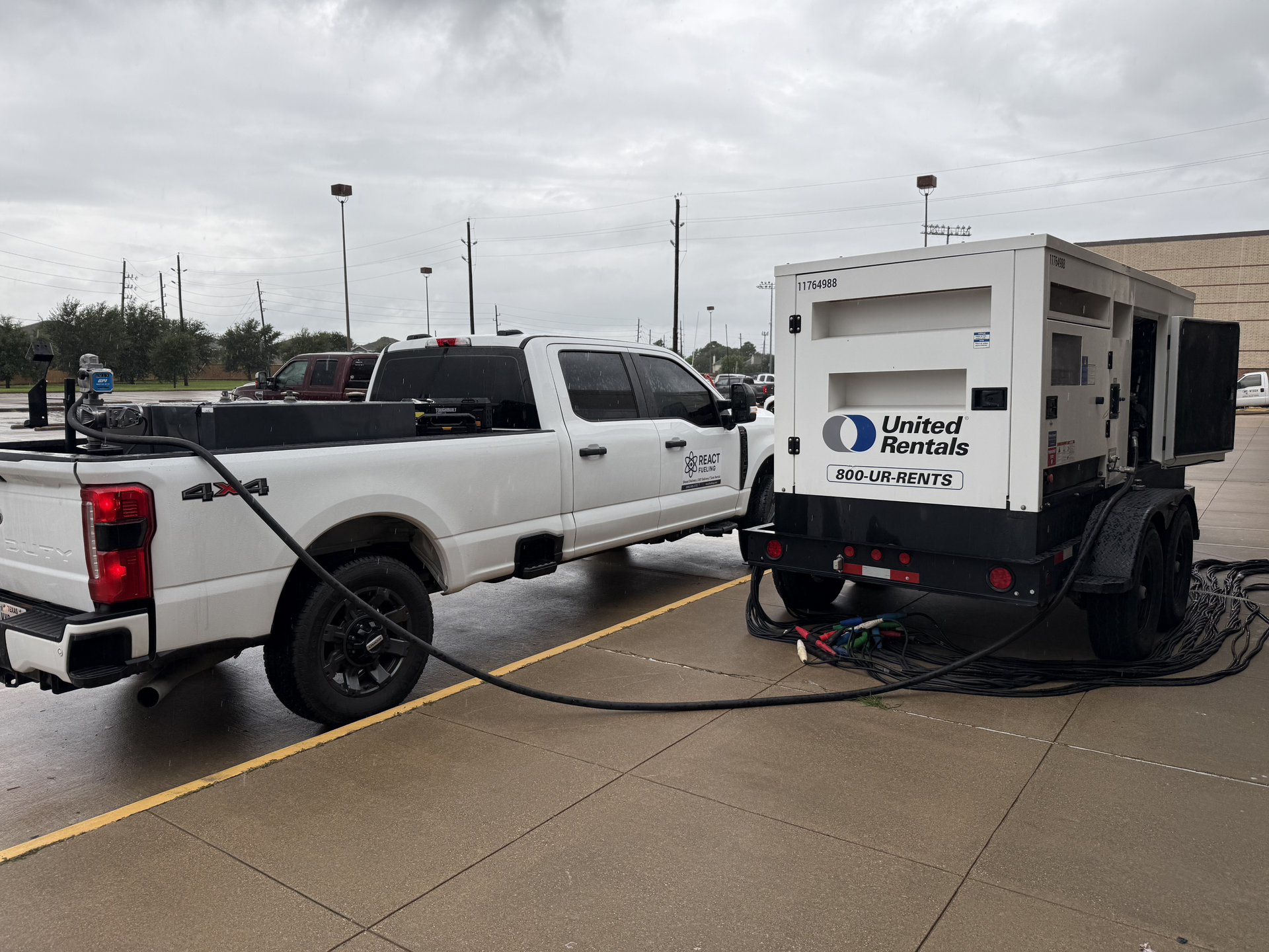 White pickup truck with utility trailer and equipment parked on a wet street under cloudy skies
