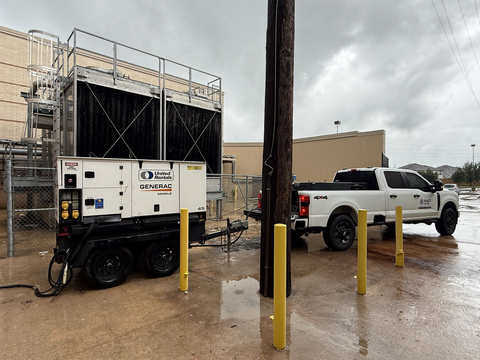 White service truck and generator at an industrial site on a rainy day