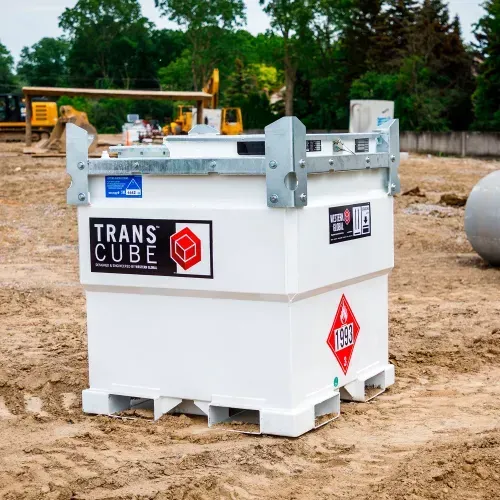 White TransCube fuel tank on sandy construction site, with metal railings and machinery in the background