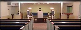 Empty church sanctuary with pews, pulpit, and stained-glass windows at the front