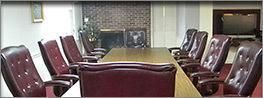 Empty conference room with a long table and maroon chairs around it