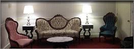 Living room with vintage sofa, two lamps, side tables, and colorful armchairs
