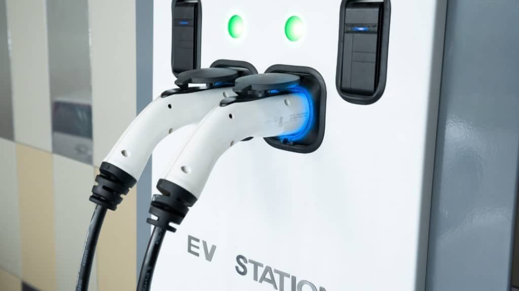 two electric cars are being charged at an ev station .