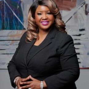 Portrait of a smiling person in a black blazer against an abstract background