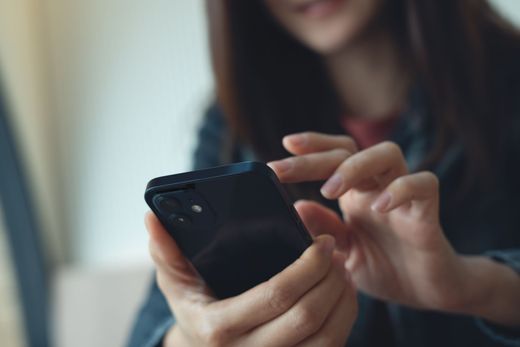 Person tapping a black smartphone indoors