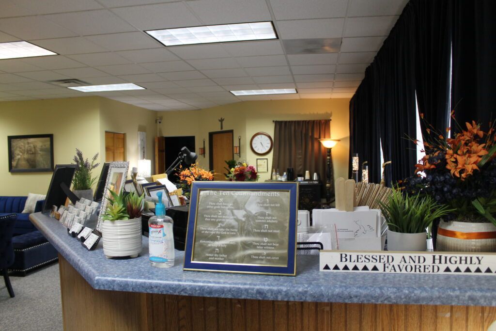 Lobby reception counter with flowers, brochures, and a framed sign in a warmly lit office