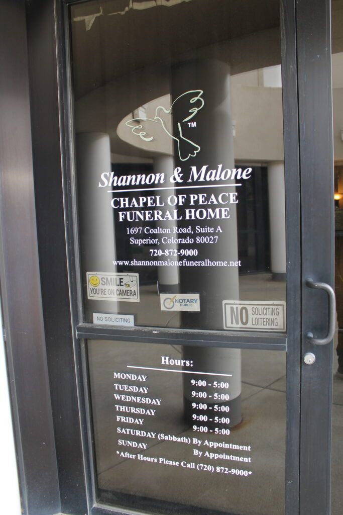 Glass door of Sherman & Hines Chapel of Peace Funeral Home with hours posted