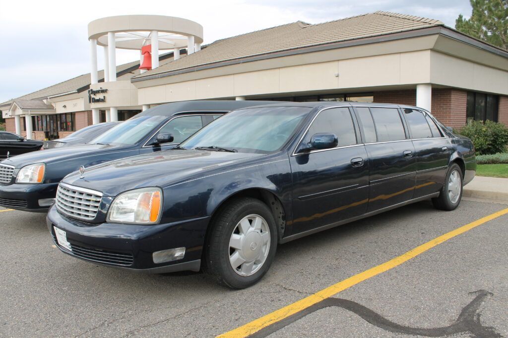 Black stretch limousine parked outside a building with a covered entrance