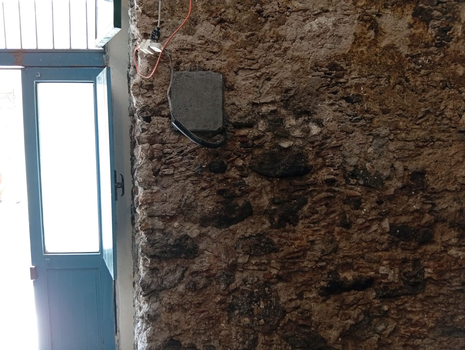 Muro di pietra grezza accanto a una porta blu con vetri satinati