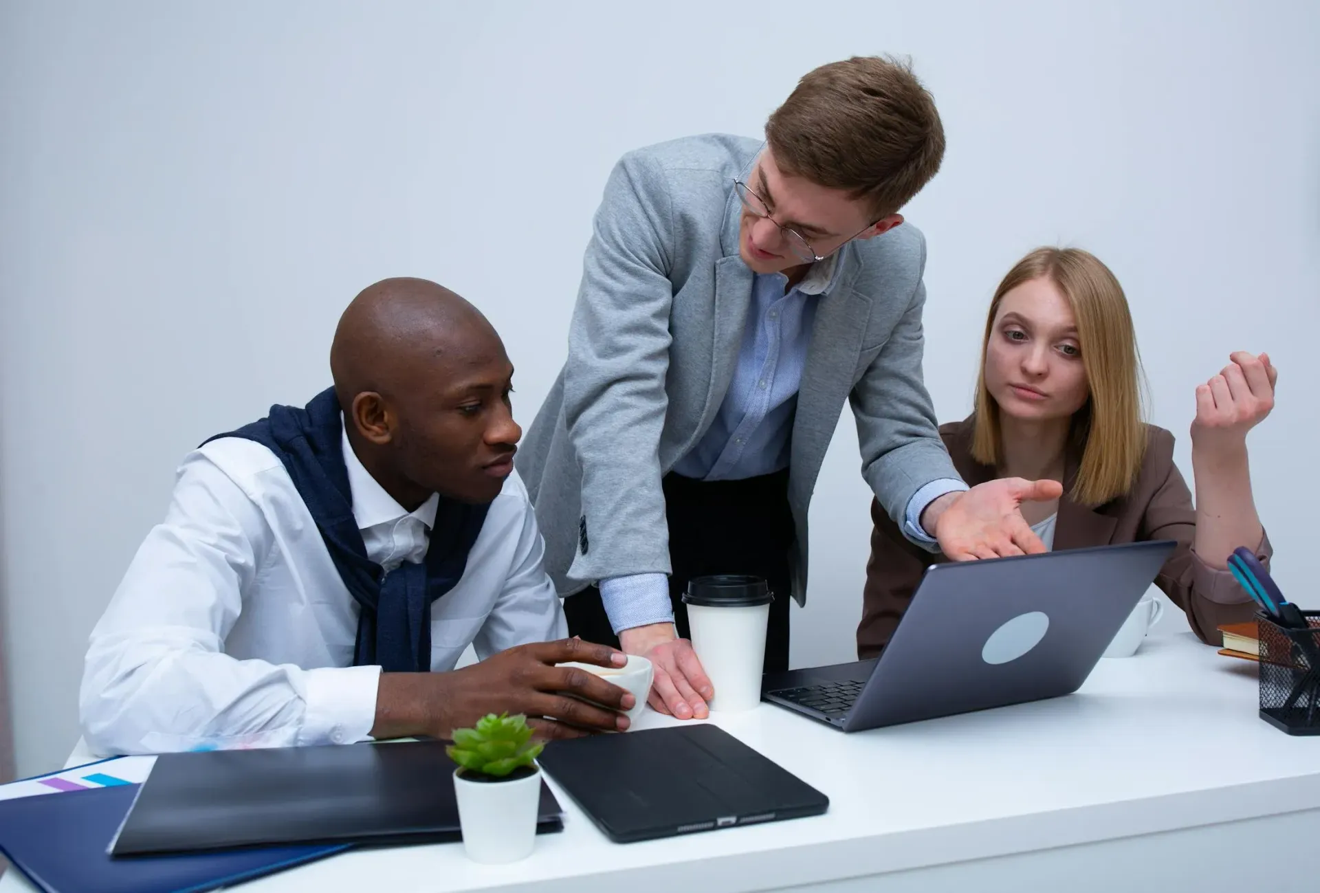 Two men are sitting on a couch looking at a laptop.