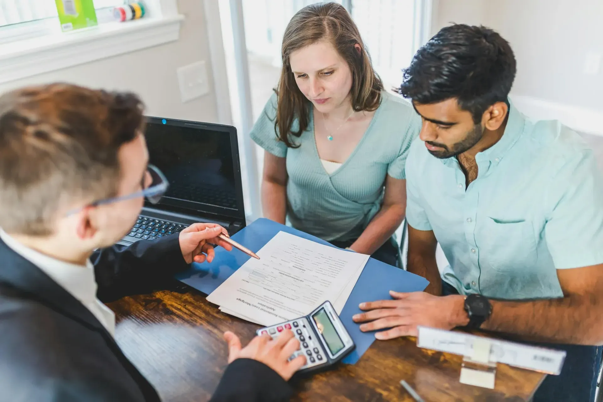 A financial advisor explaining Employee Stock Ownership Plan (ESOP) documents to a couple at a desk.