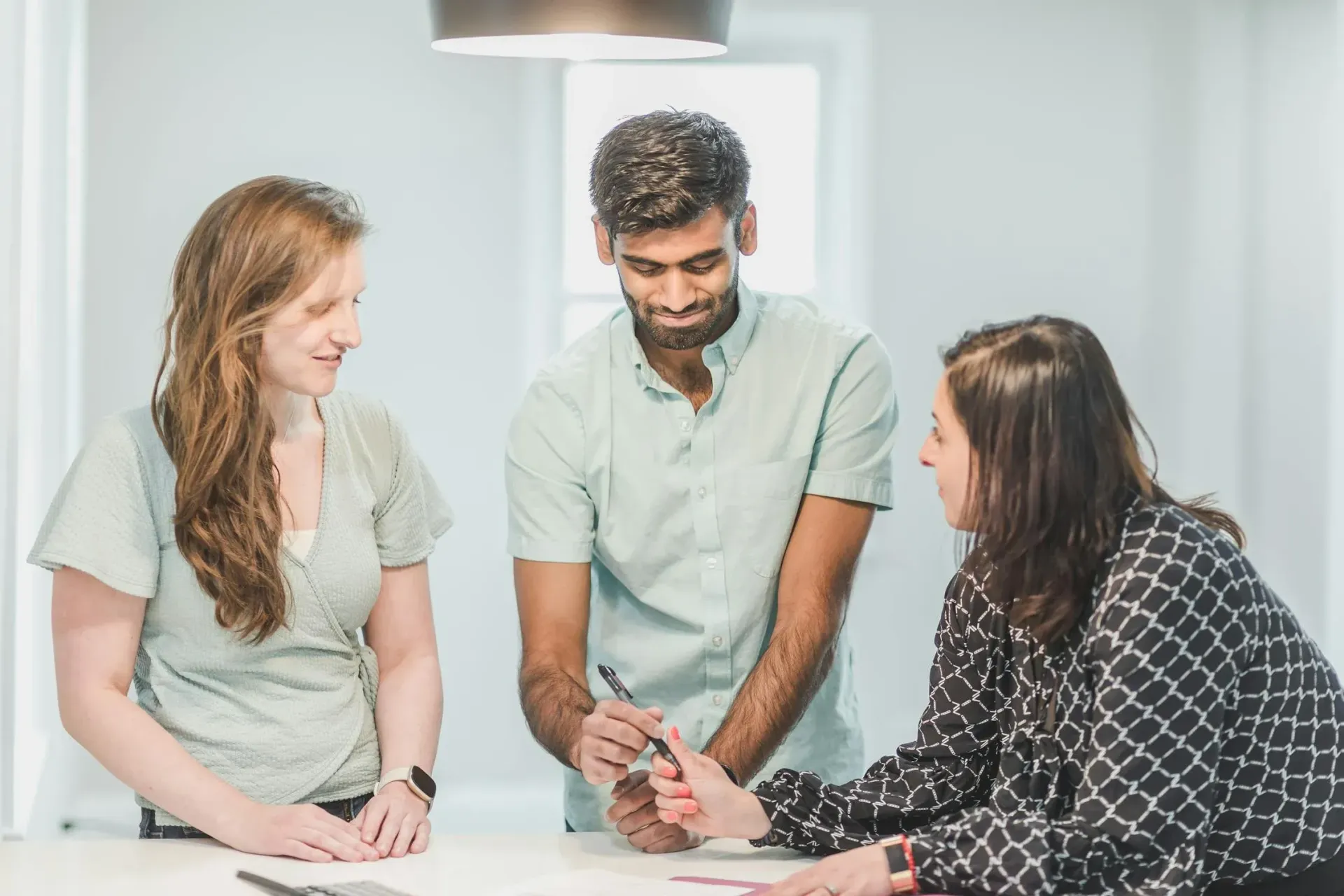 Diverse team collaborating on document in bright office space.