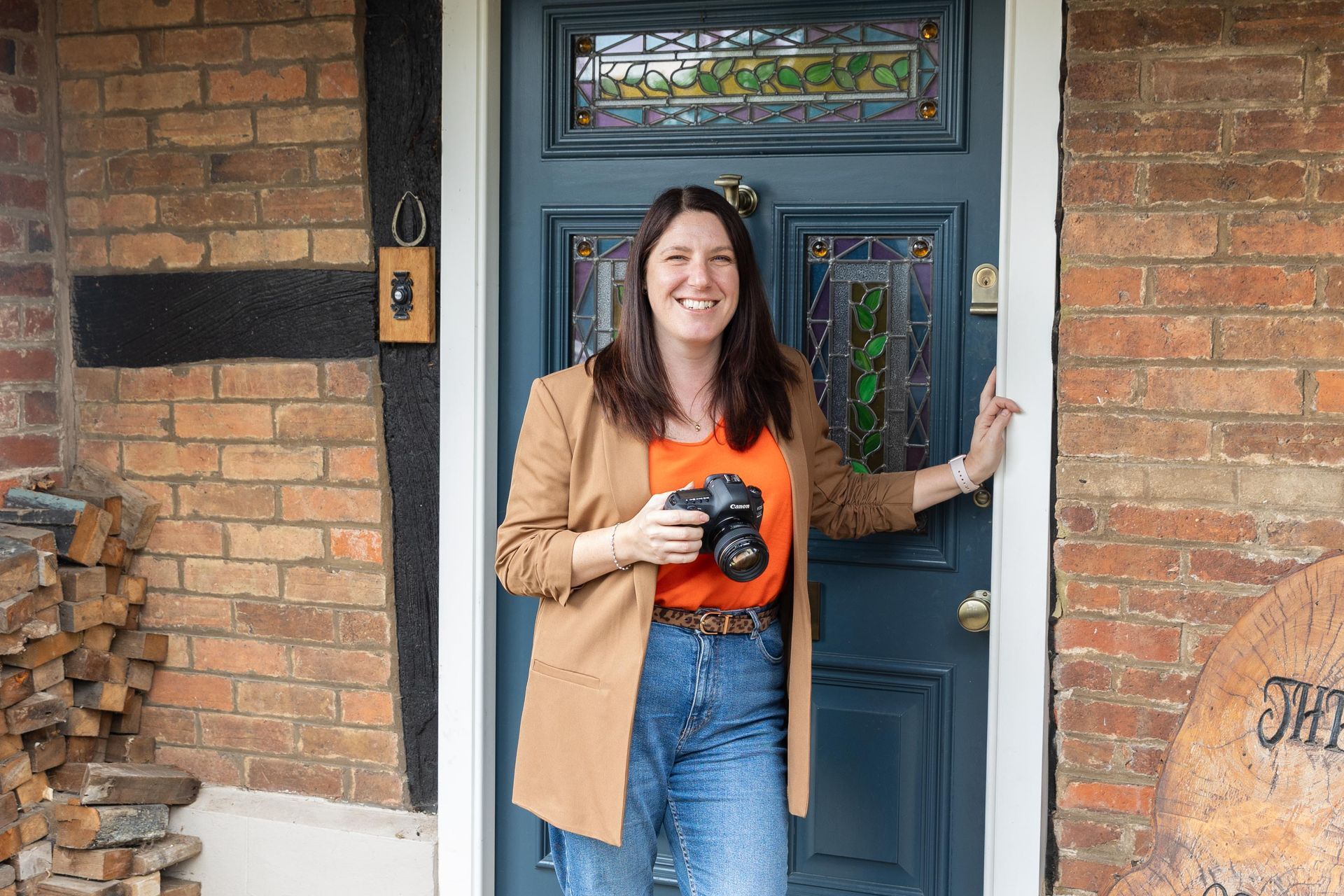 Woman standing at a front door holding a camera