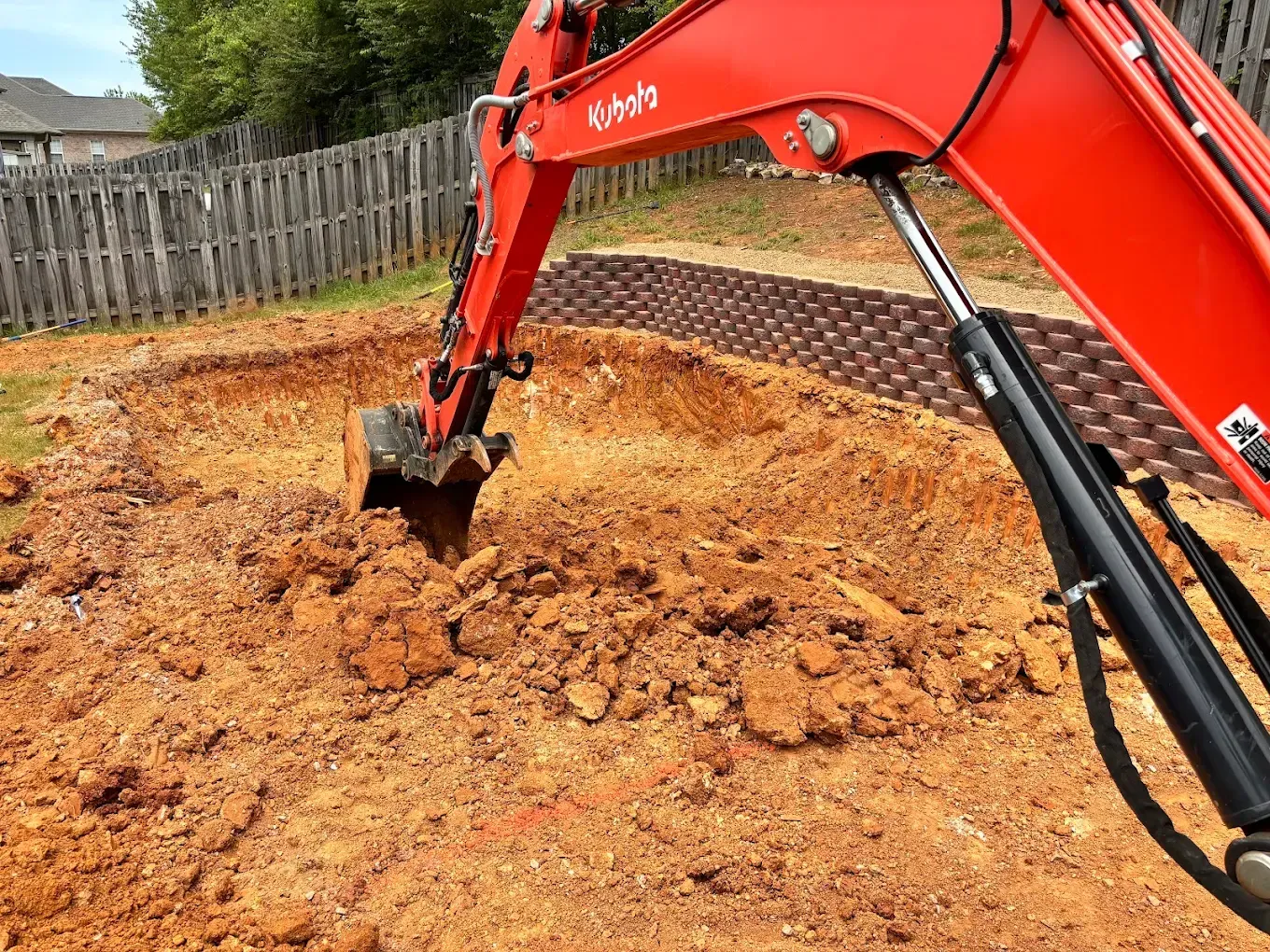 Orange excavator digging dirt in a backyard construction site