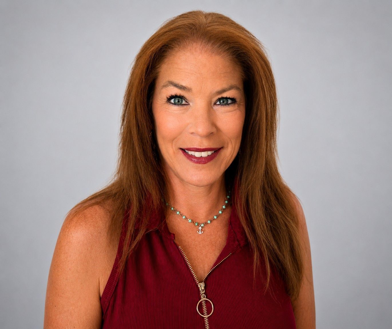 Portrait of a smiling woman in a red top against a gray background