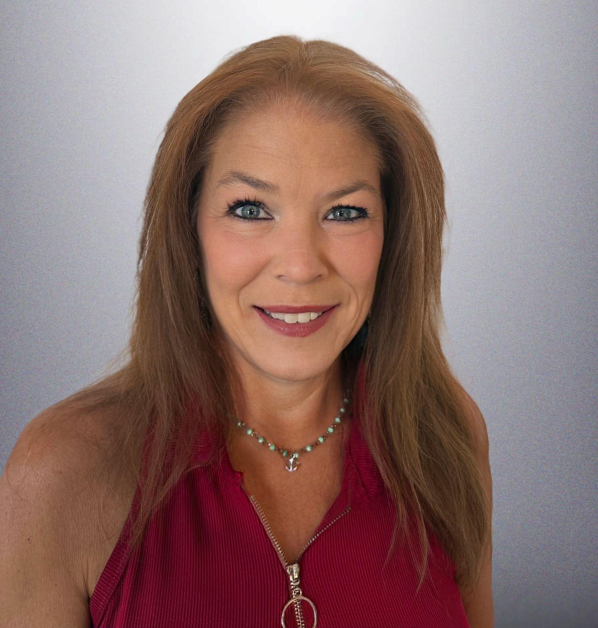 Portrait of a smiling woman in a red top against a gray background