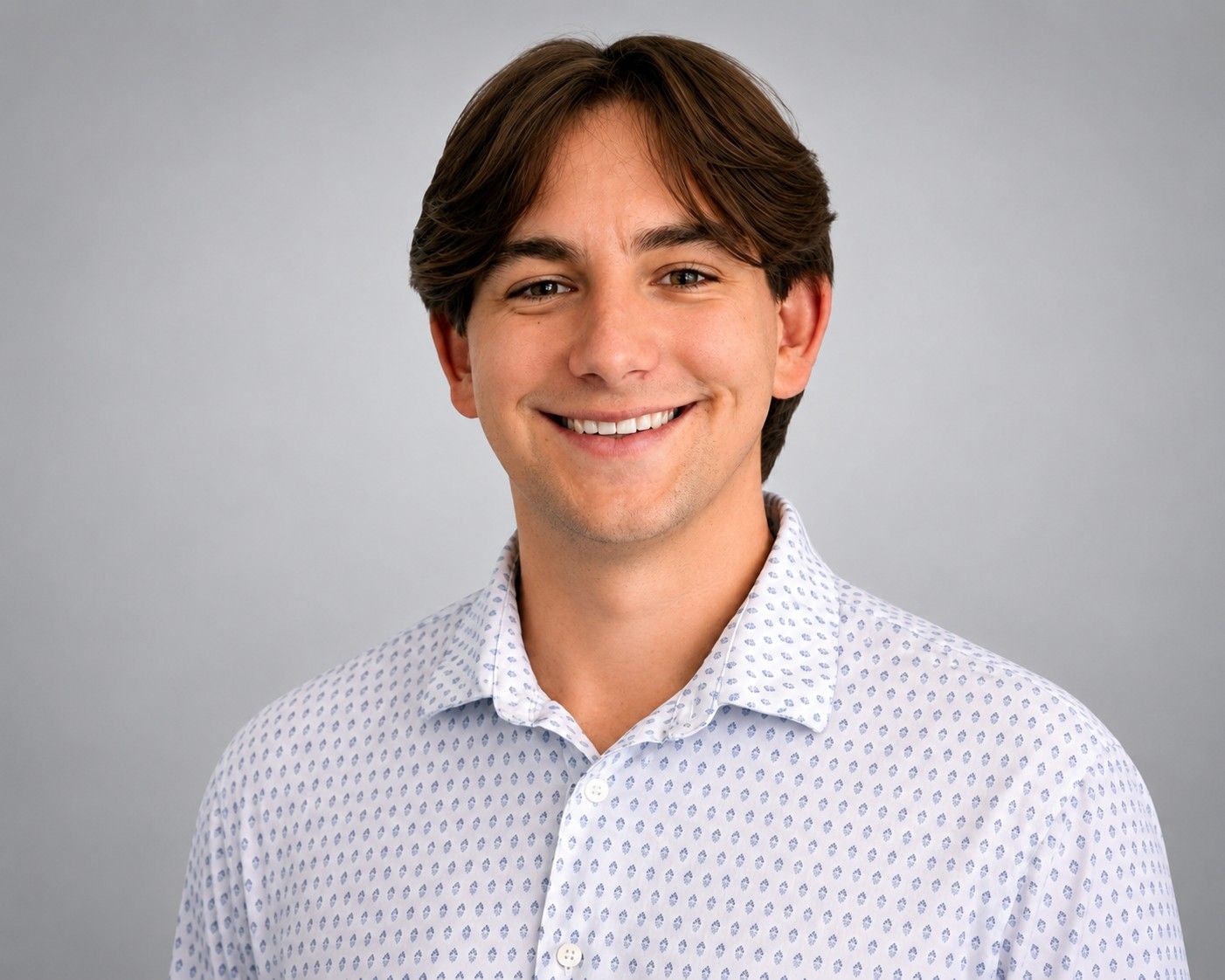 Smiling person in a white patterned shirt against a light gray background