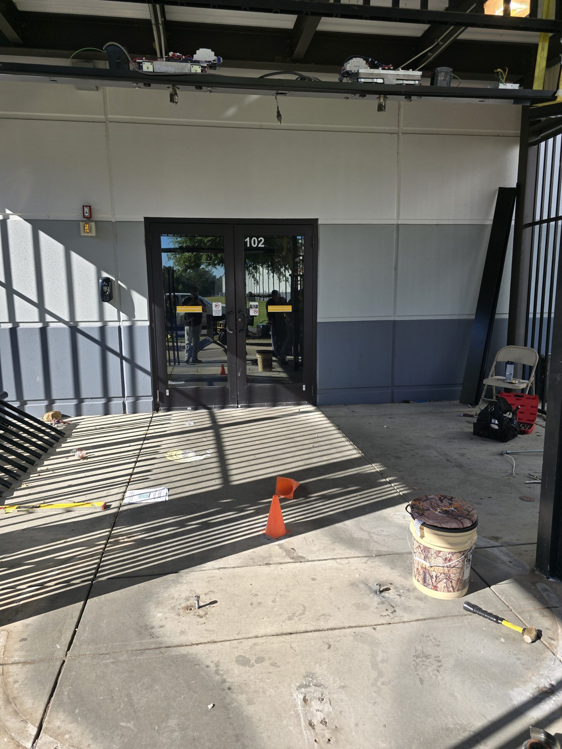 Exterior of a building entrance with double doors, concrete ramp, and a seated scooter nearby.