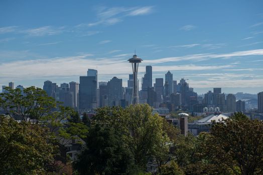 Seattle skyline with the Space Needle above green trees under a blue sky