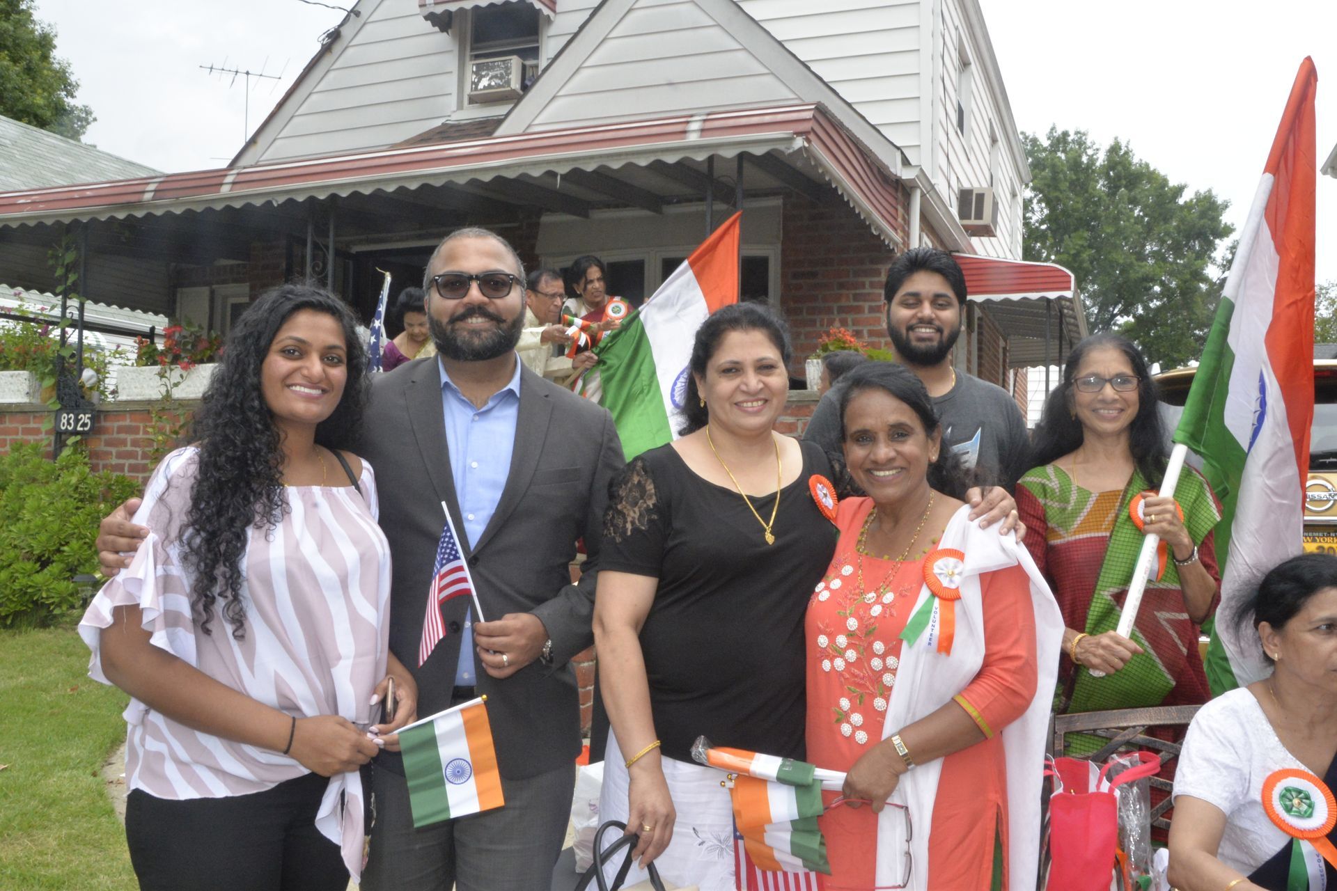 A group of people standing in front of a house holding flags.