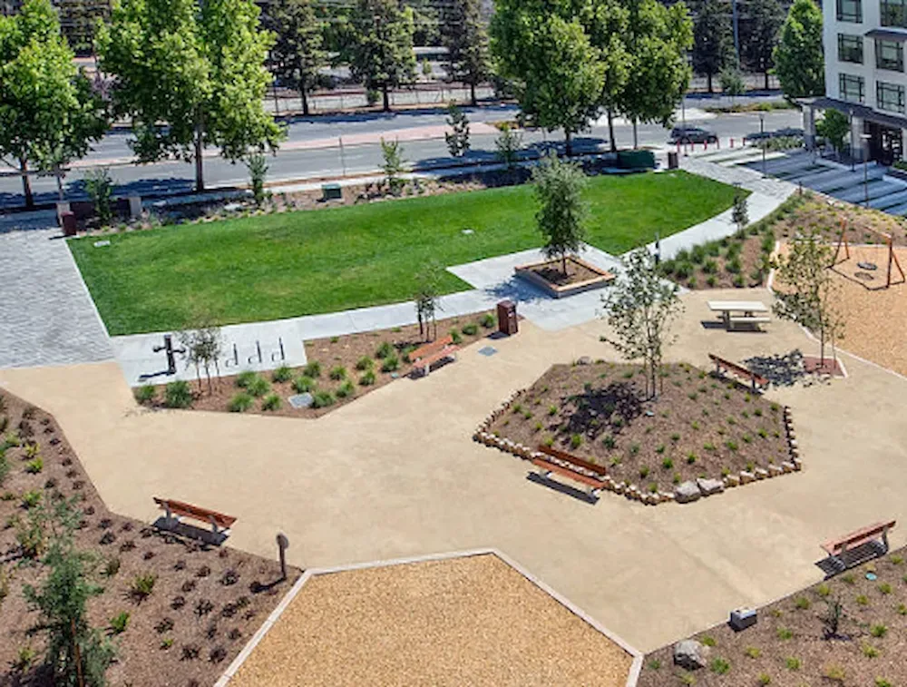 Aerial view of a landscaped park with paths, benches, trees, and green lawns.