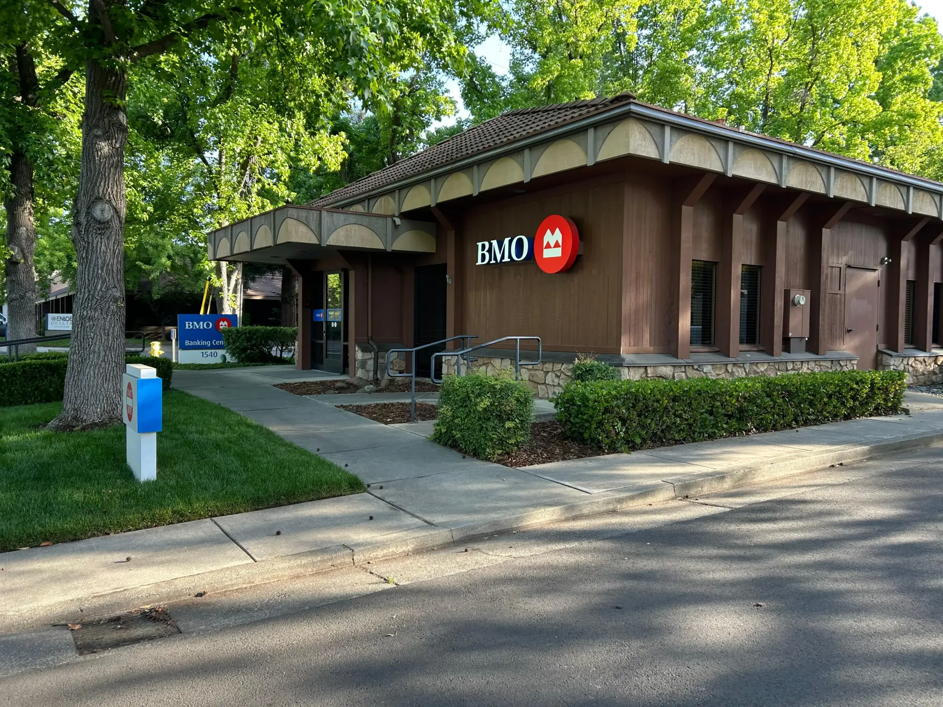 BMO bank branch on a tree-lined street, with brown exterior and red logo sign