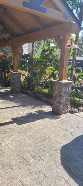 Landscaped front yard with a curved walkway beside a brick house under a blue sky