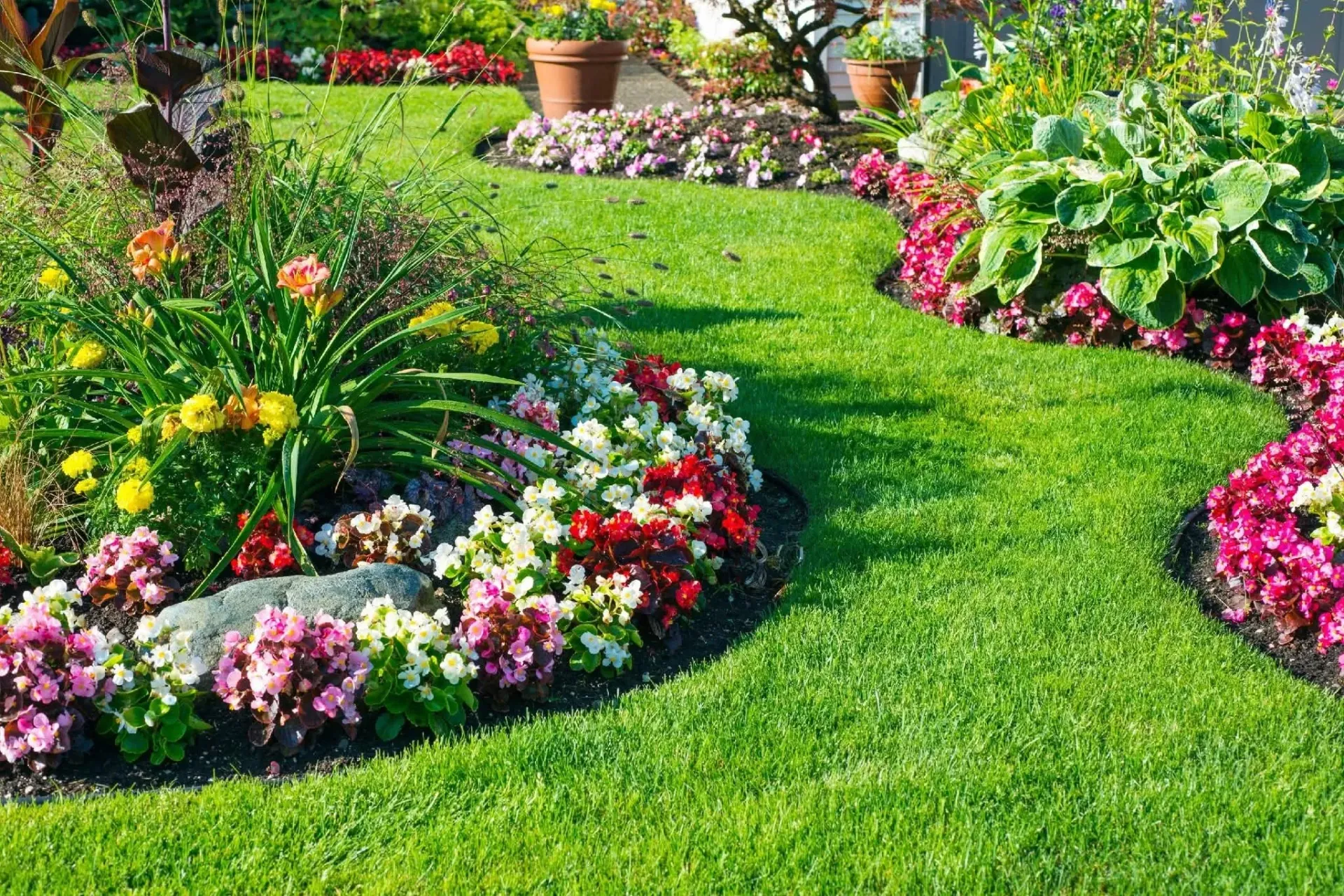 Colorful flower beds and lush green lawn in a landscaped garden path