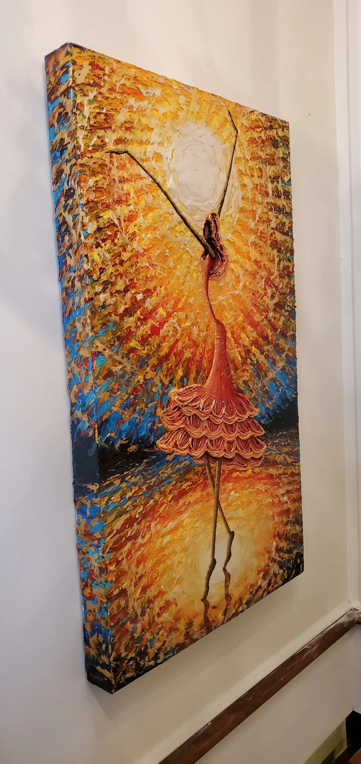 Painting of a ballerina in a golden light, arms raised, with a reflection in the water.