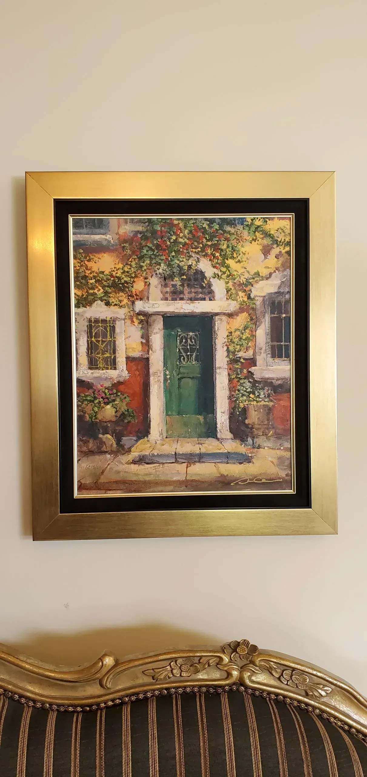 Painting of a green door with a gold frame hanging on a wall, above an ornate chair.
