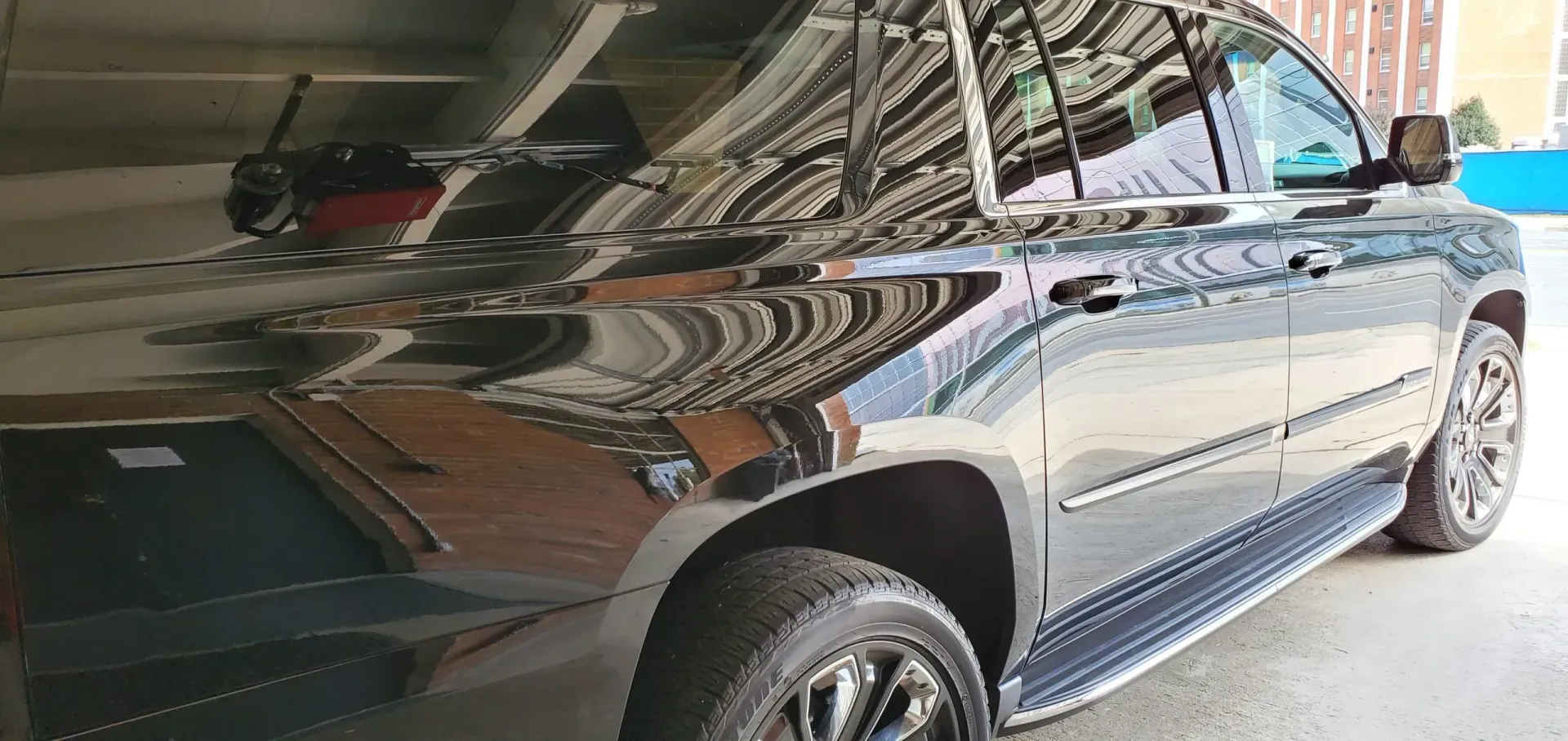 Black SUV parked in a garage, reflecting the surroundings.