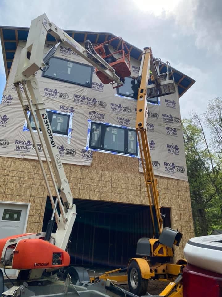 A crane is sitting in front of a house under construction.