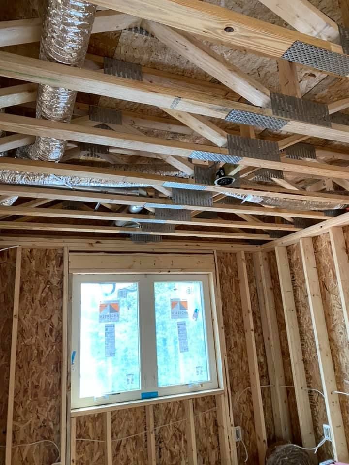 A room in a house under construction with a window and wooden beams.