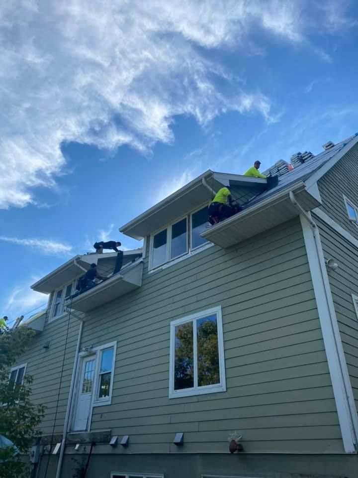 A group of people are working on the roof of a house.