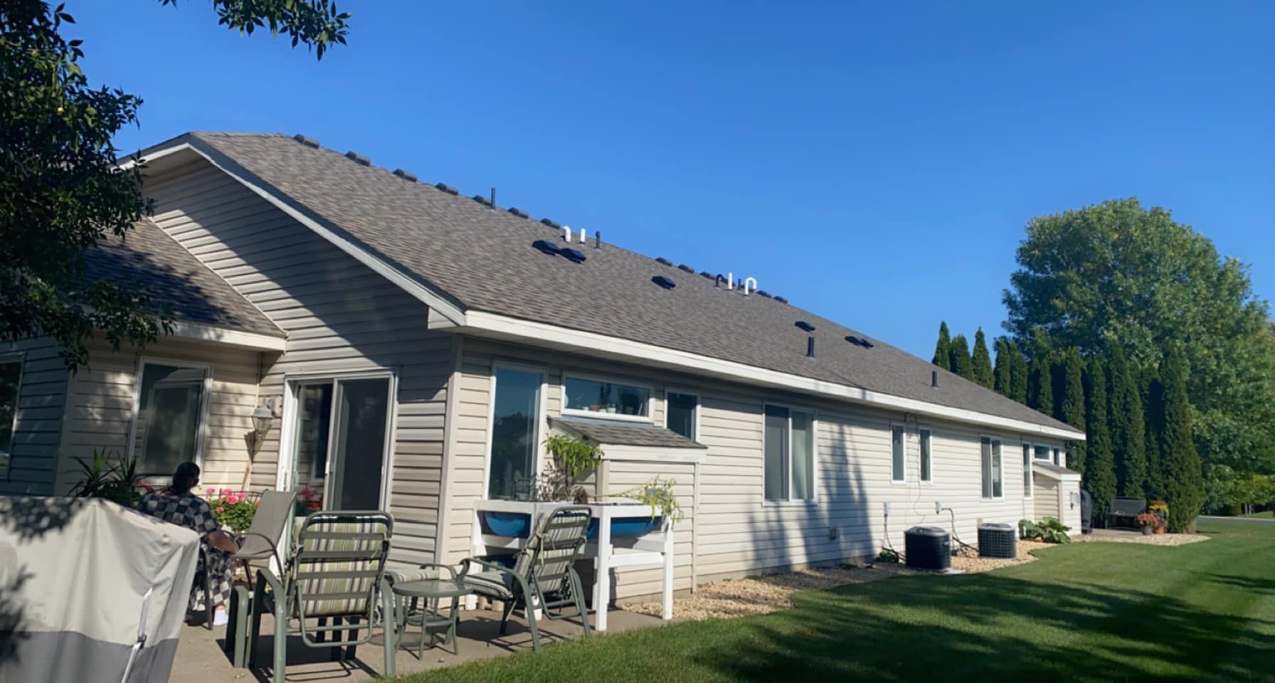 The back of a house with a patio and chairs in front of it.