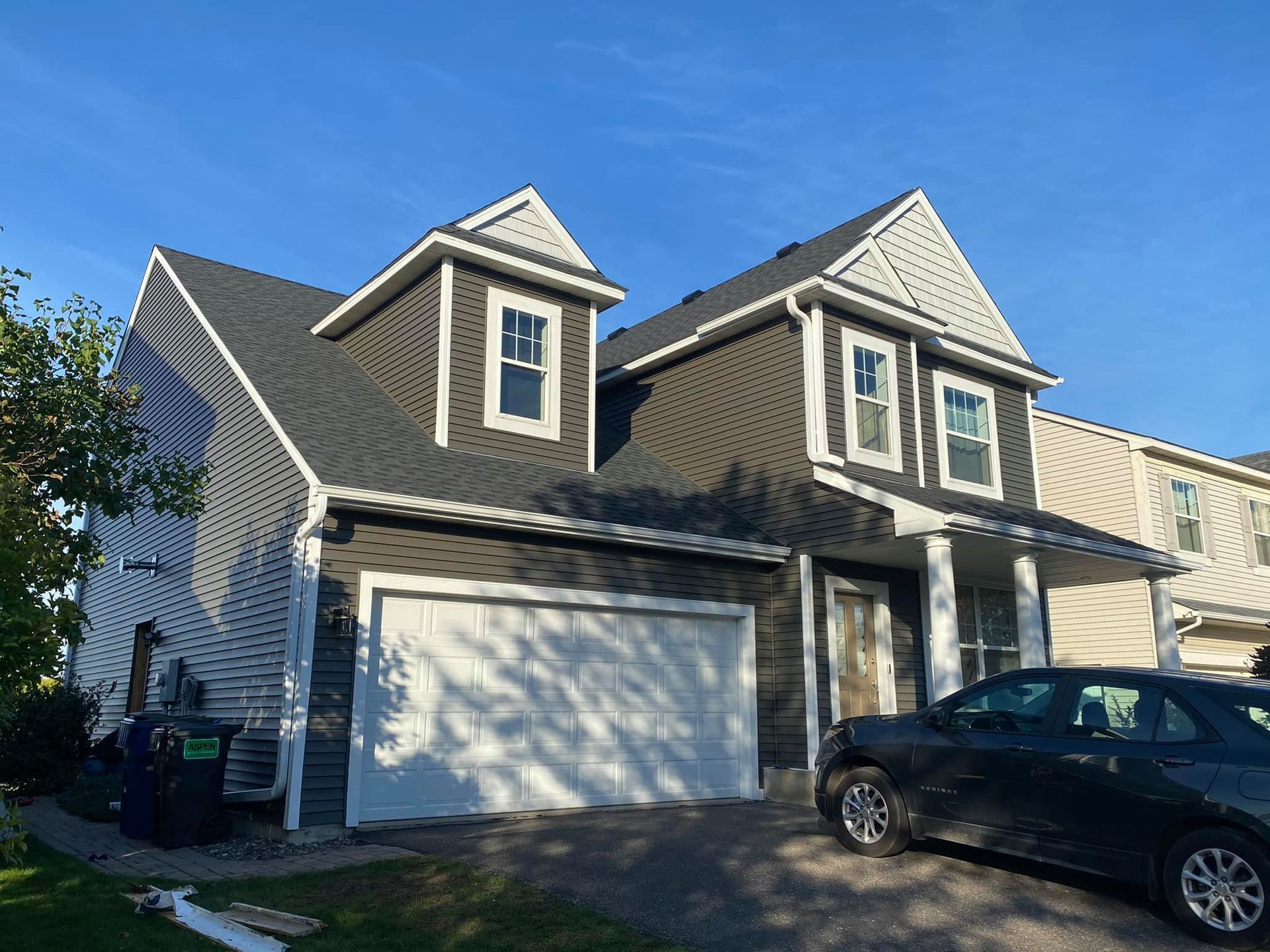 A car is parked in front of a house with a garage.
